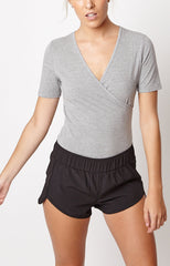 Body mujer gris cruzado, prenda deportiva y casual, manga corta, escote en V, cierre práctico con botones a presión, cómodo para outfits urbanos o fitness, disponible talla L, tendencia actual, fácil de combinar. ✅Entrega 24/48h